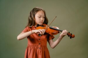 A young girl playing a violin with focus and concentration in a studio setup.